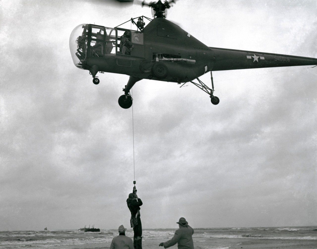 Joseph Pawlik, captain of the barge aground on Penfield Reef, off Fairfield, CT, is lowered to safety from a Sikorsky R-5 helicopter piloted by Jimmy Viner, the company chief pilot, assisted by Capt. Jack Beighle of the Army Air Force. Nov. 29, 1945